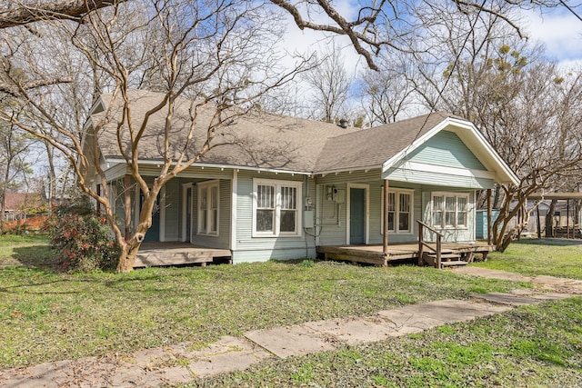 view of front of property with covered porch, a shingled roof, and a front yard