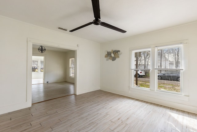 unfurnished room featuring crown molding, light wood finished floors, visible vents, and a ceiling fan