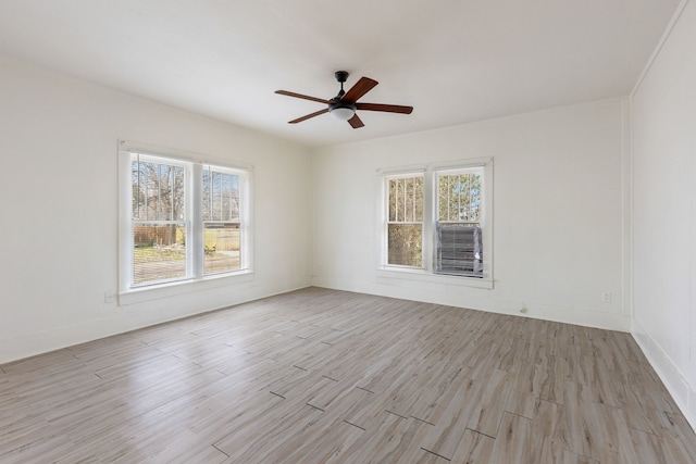 spare room with plenty of natural light, light wood-style flooring, baseboards, and ceiling fan