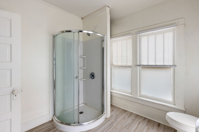 full bathroom with toilet, a stall shower, ornamental molding, and wood finished floors