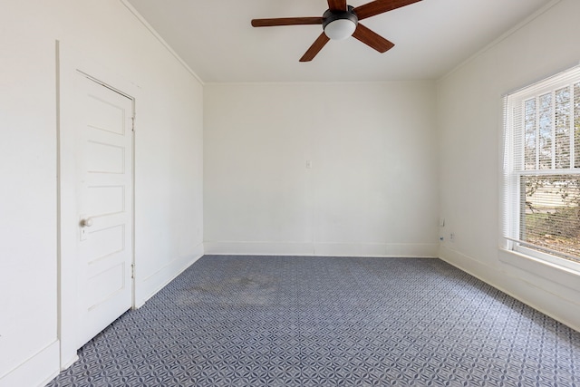 unfurnished room featuring baseboards, dark colored carpet, ceiling fan, and crown molding