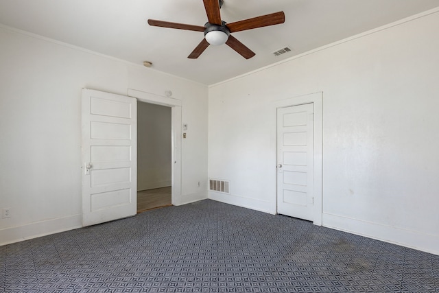 unfurnished bedroom with baseboards, visible vents, dark colored carpet, and crown molding