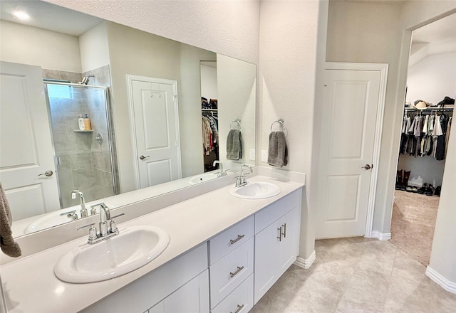 bathroom with a sink, a shower stall, baseboards, and double vanity