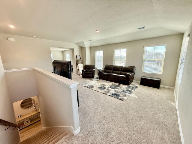 living area featuring light colored carpet, visible vents, baseboards, and a textured ceiling