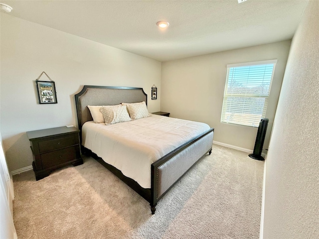 bedroom featuring light carpet, baseboards, and a textured ceiling