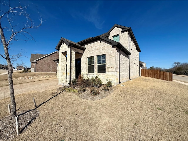 view of home's exterior with stone siding and fence