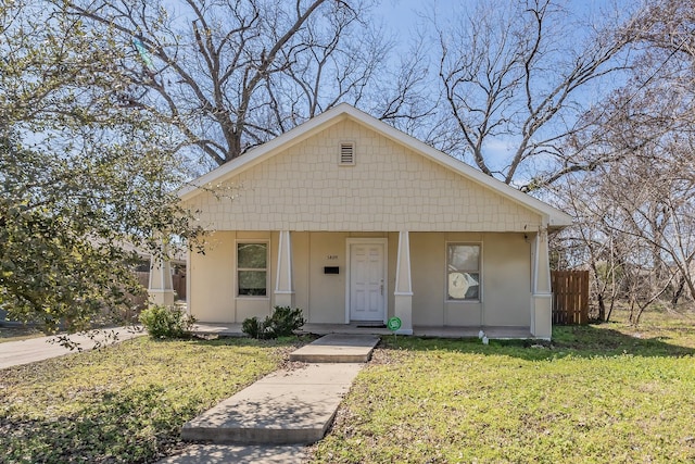 bungalow with a front yard, fence, and stucco siding