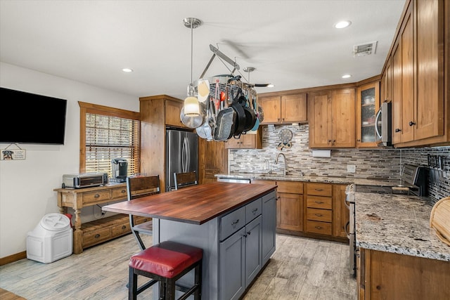 kitchen featuring visible vents, dark stone counters, a center island, stainless steel appliances, and pendant lighting