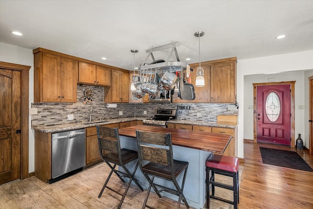 kitchen with appliances with stainless steel finishes, decorative light fixtures, a sink, and light stone countertops