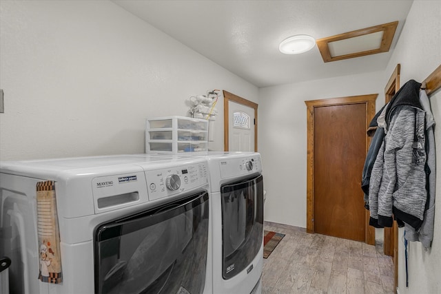 washroom with light wood finished floors, attic access, washer and dryer, laundry area, and baseboards