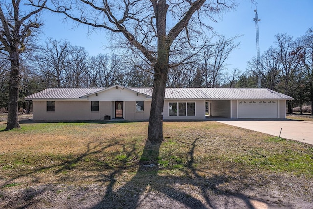 single story home featuring an attached garage, metal roof, a front lawn, and concrete driveway