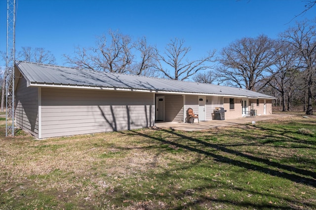 back of house featuring a yard, metal roof, and a patio