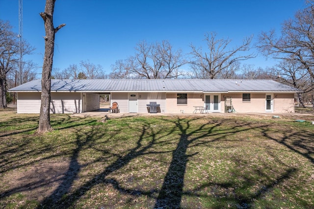 back of property featuring a yard, metal roof, french doors, and a patio area