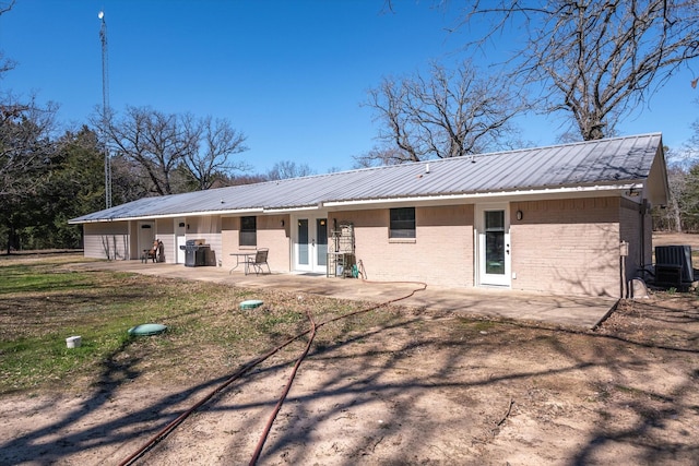 back of property featuring a patio area, metal roof, and brick siding