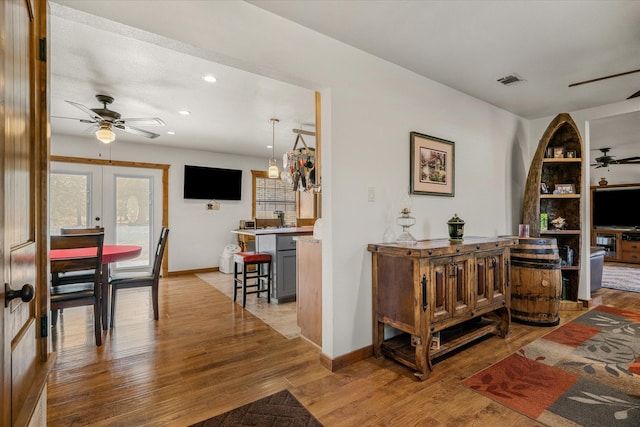 interior space with ceiling fan, french doors, visible vents, and light wood-style floors