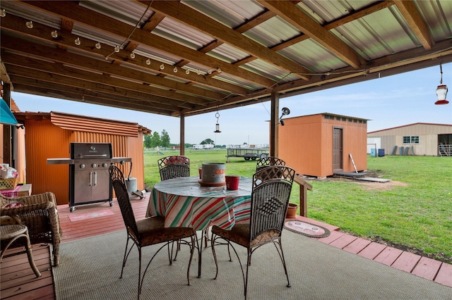 view of patio with an outbuilding, area for grilling, a wooden deck, a shed, and outdoor dining space