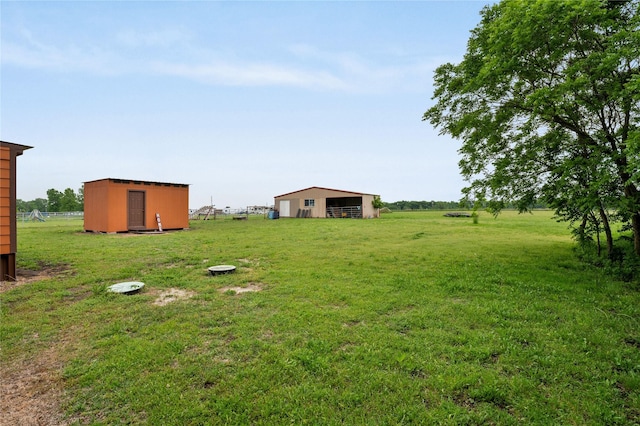 view of yard with a rural view, a pole building, fence, and an outdoor structure