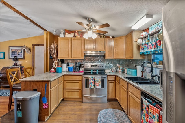 kitchen with light stone counters, under cabinet range hood, wood finished floors, a sink, and appliances with stainless steel finishes