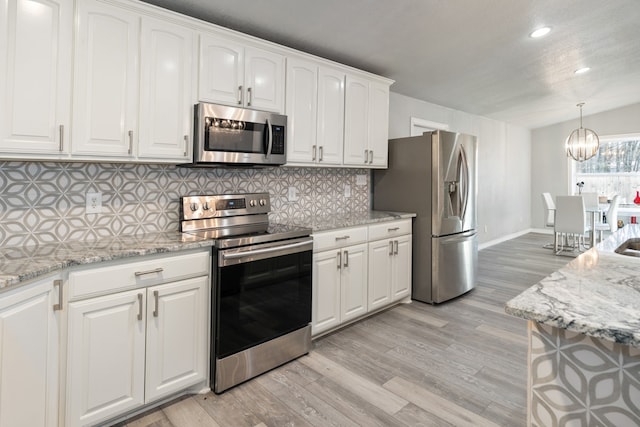 kitchen featuring stainless steel appliances, light wood-type flooring, white cabinetry, and light stone countertops