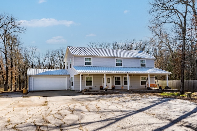 view of front of home with metal roof, a porch, aphalt driveway, an attached garage, and fence