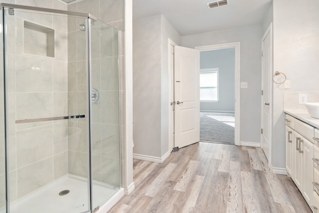 full bath featuring a shower stall, baseboards, wood finished floors, and vanity