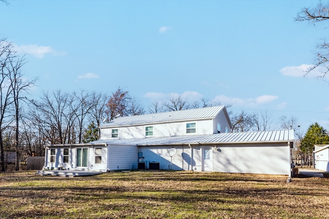 rear view of property with a standing seam roof, central AC, metal roof, and a lawn