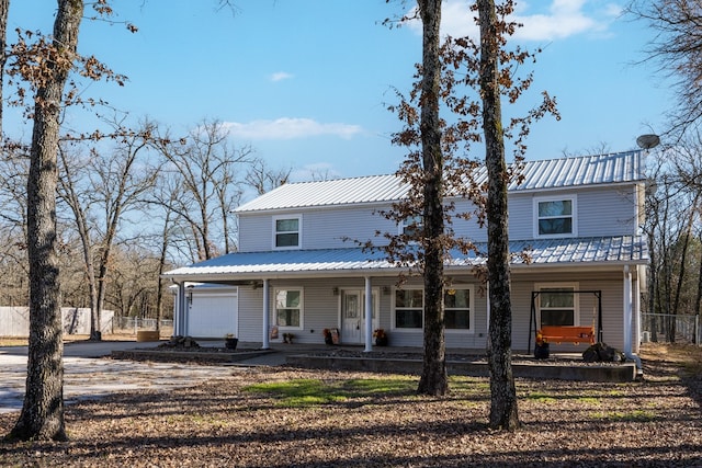 view of front of home with covered porch, metal roof, fence, and driveway