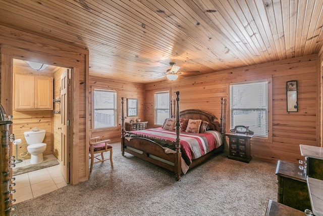 bedroom featuring ensuite bath, wood walls, tile patterned flooring, and carpet flooring