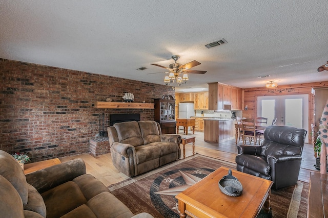 living room with visible vents, ceiling fan, a textured ceiling, and light wood finished floors