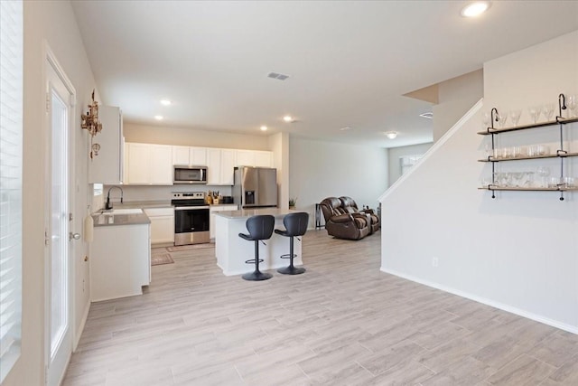 kitchen with stainless steel appliances, visible vents, white cabinetry, open floor plan, and a center island