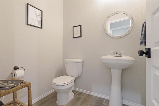 bathroom featuring baseboards, toilet, and wood tiled floor