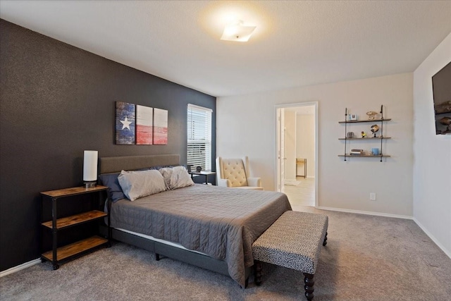 carpeted bedroom with ensuite bath and baseboards