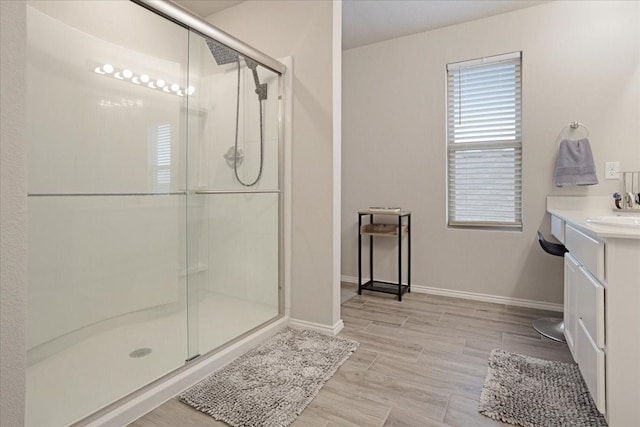 full bathroom featuring a stall shower, wood finish floors, vanity, and baseboards