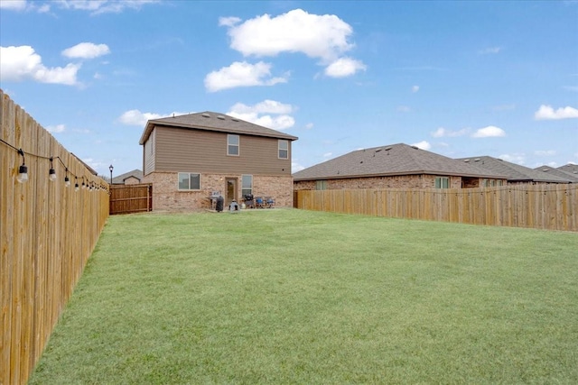 back of property featuring brick siding, a lawn, and a fenced backyard