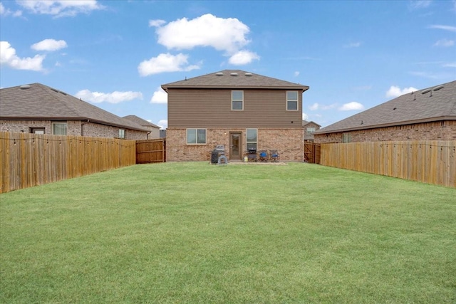 rear view of house with brick siding, a lawn, and a fenced backyard