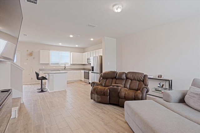 living area featuring light wood finished floors, visible vents, and recessed lighting