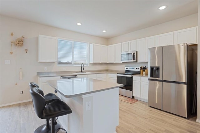 kitchen with a center island, light countertops, appliances with stainless steel finishes, white cabinetry, and a sink