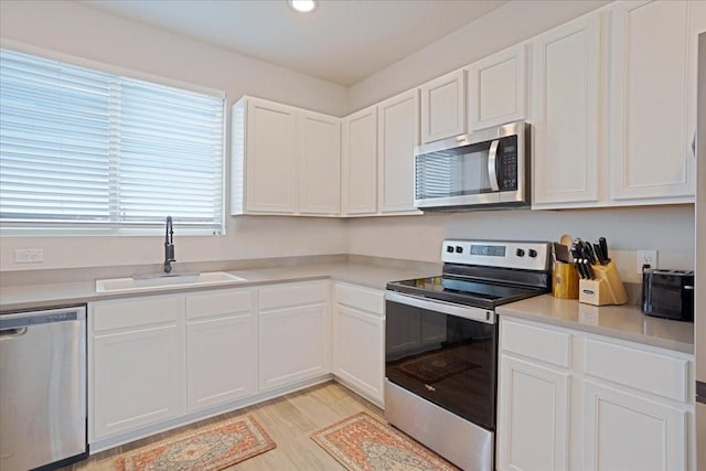 kitchen featuring white cabinetry, appliances with stainless steel finishes, light countertops, and a sink