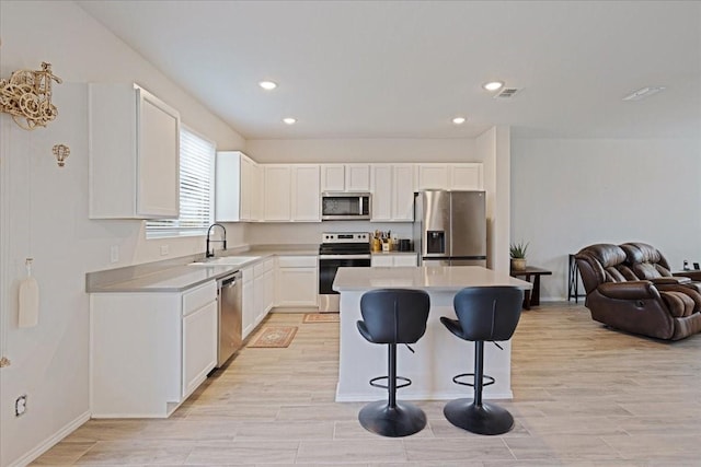 kitchen with stainless steel appliances, white cabinets, open floor plan, light countertops, and a center island