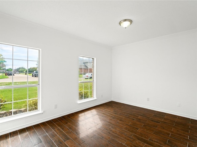 spare room featuring crown molding, dark wood finished floors, and baseboards