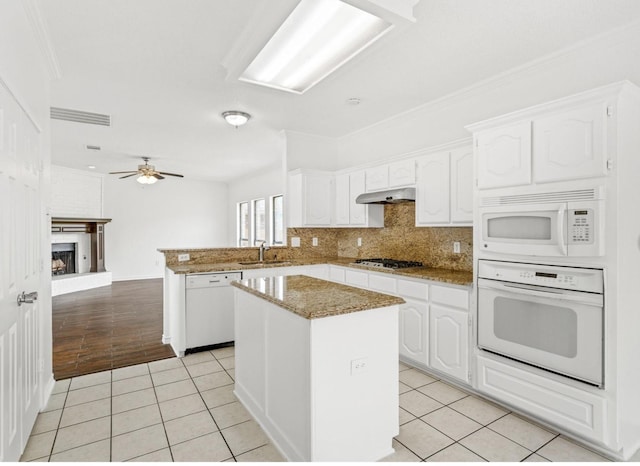 kitchen featuring white appliances, light tile patterned flooring, a sink, and a center island