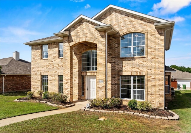 traditional-style home with brick siding and a front lawn