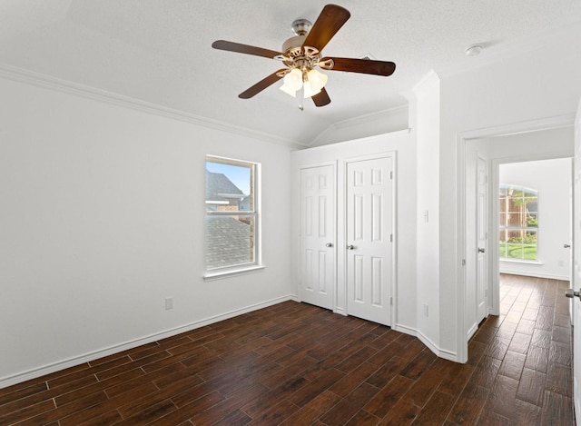 unfurnished bedroom with crown molding, vaulted ceiling, dark wood finished floors, and baseboards