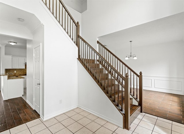 stairs featuring a chandelier, a decorative wall, tile patterned flooring, and crown molding