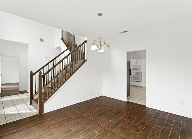 interior space with dark wood-style floors, visible vents, an inviting chandelier, baseboards, and stairs