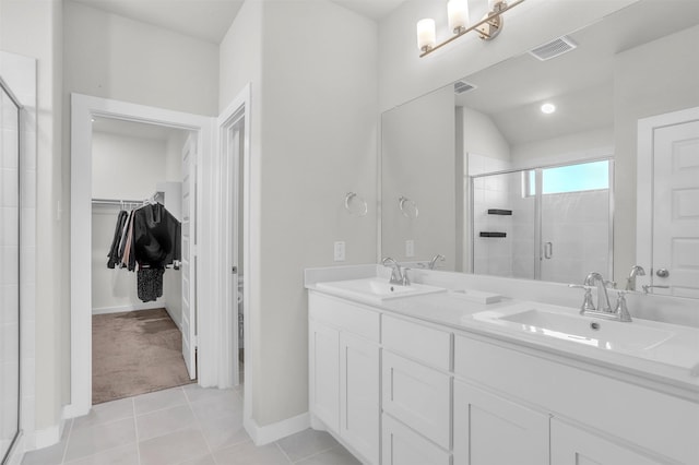 full bathroom featuring a stall shower, a sink, a spacious closet, and tile patterned floors