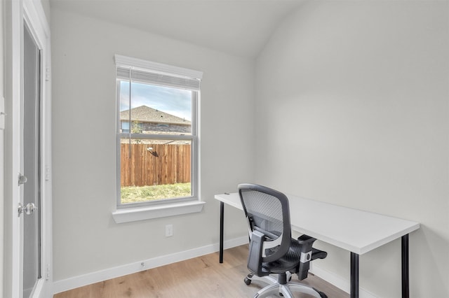 office space with a healthy amount of sunlight, baseboards, vaulted ceiling, and wood finished floors