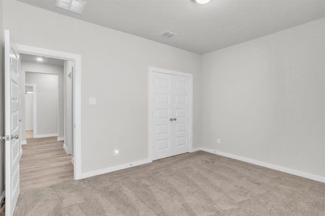 unfurnished bedroom with carpet floors, baseboards, visible vents, and a closet