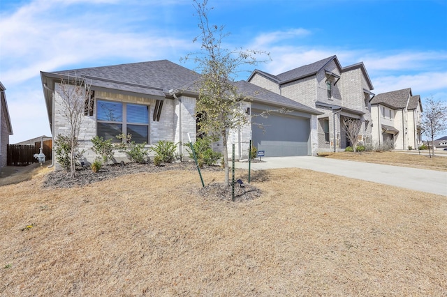 view of front facade featuring driveway, an attached garage, and a shingled roof