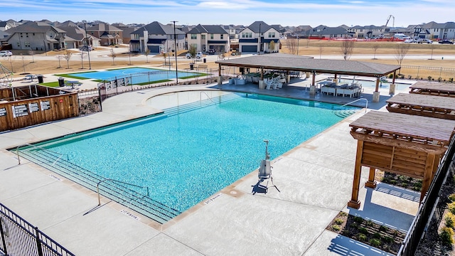 community pool with a residential view, fence, and a patio